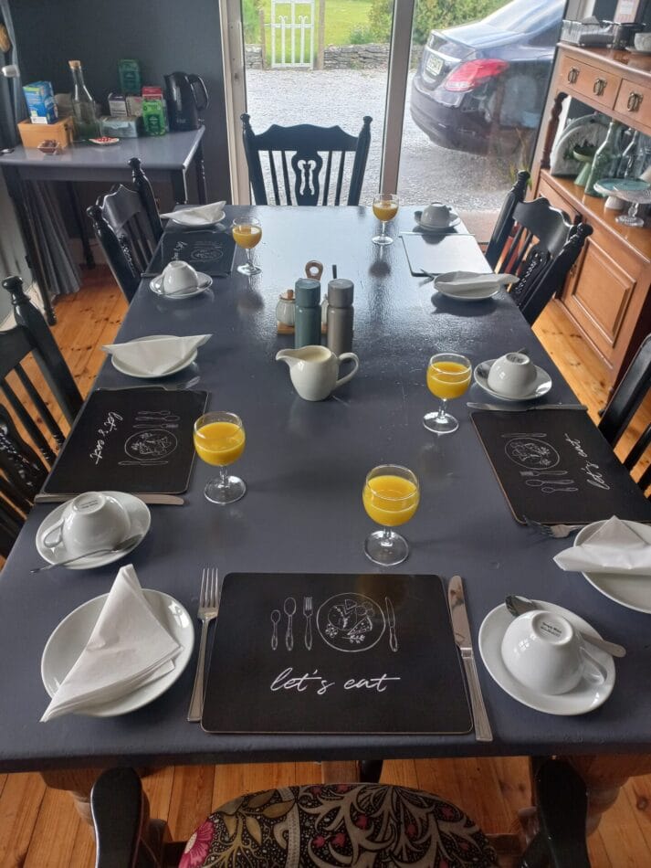 Breakfast table set at An Riasc B&B in Dingle, with juice, cups, and mountain view